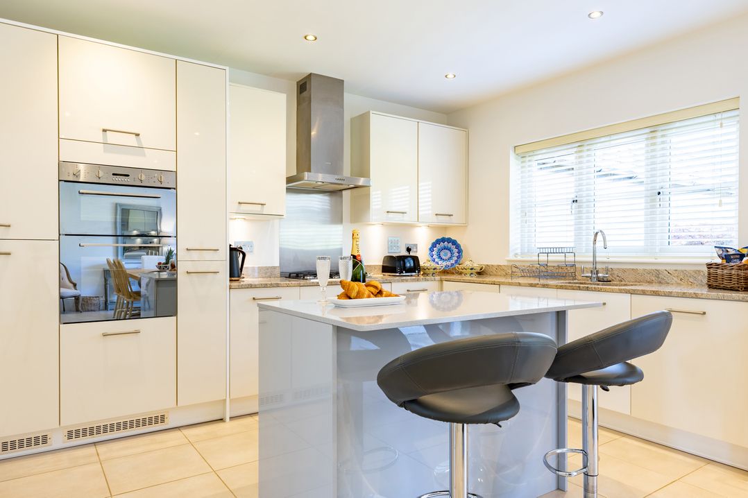 A kitchen with cabinets, countertop, and bar stools at Old Railway Close Lechlade-On-Thames
