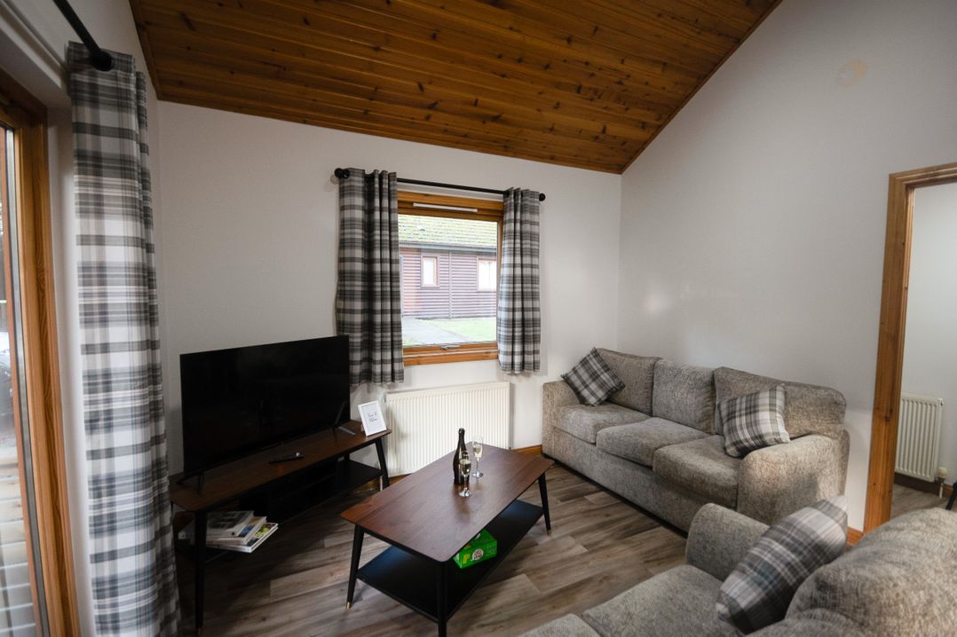A living room with a sofa and television at Sidlaw Spa (Pet) Fowlis near Dundee