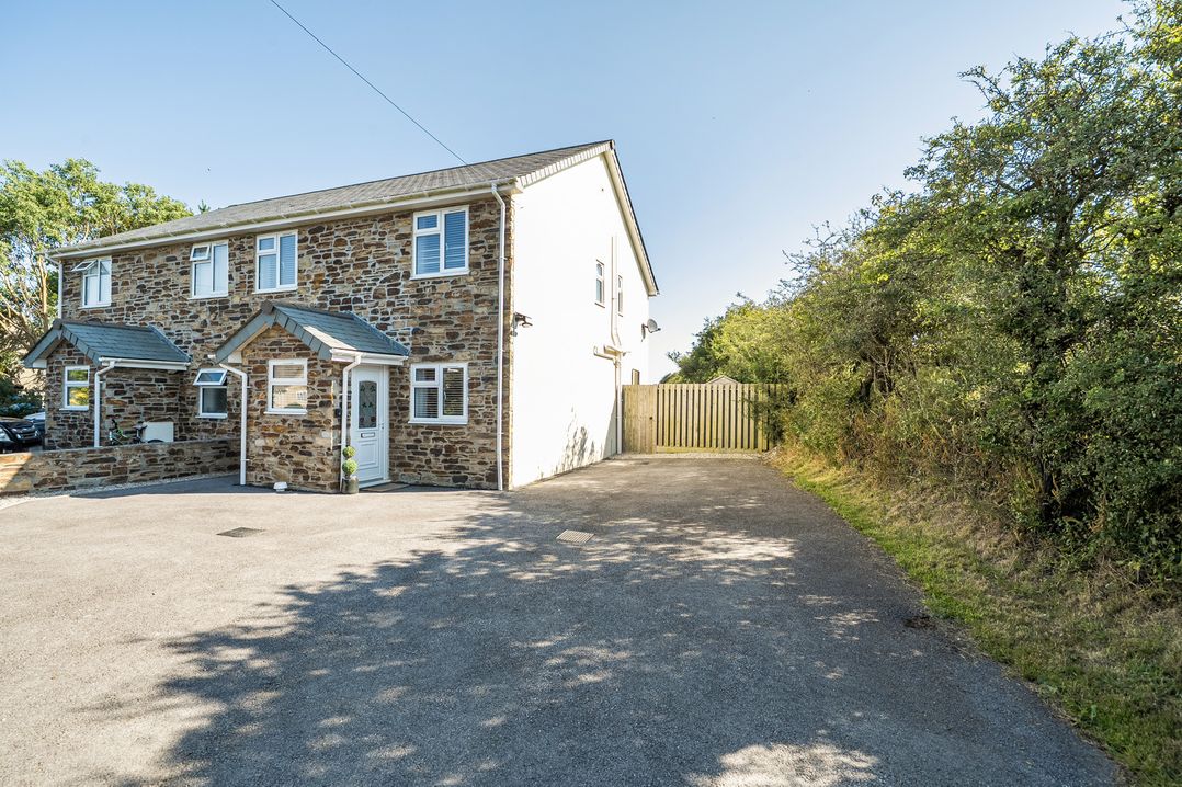 A house with a driveway and fence at Buttercup Cottage in St Merryn