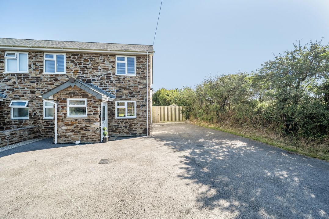 An outdoor view of a stone house with a driveway at Buttercup Cottage St Merryn