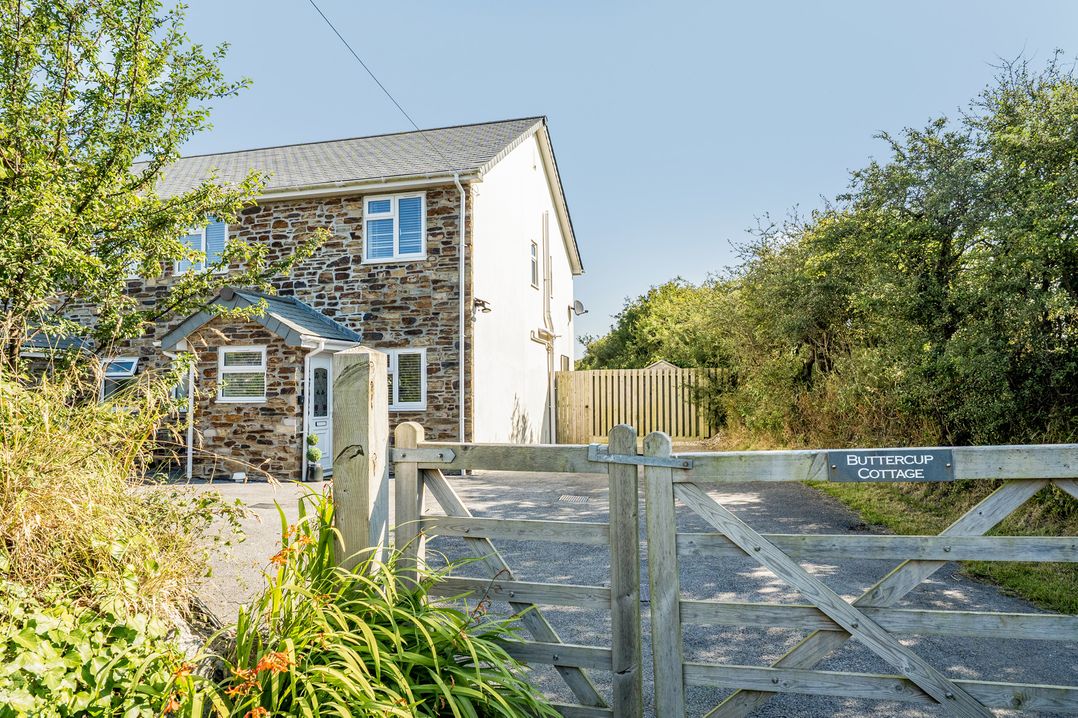 An outdoor area with a gate and a cottage at Buttercup Cottage in St Merryn