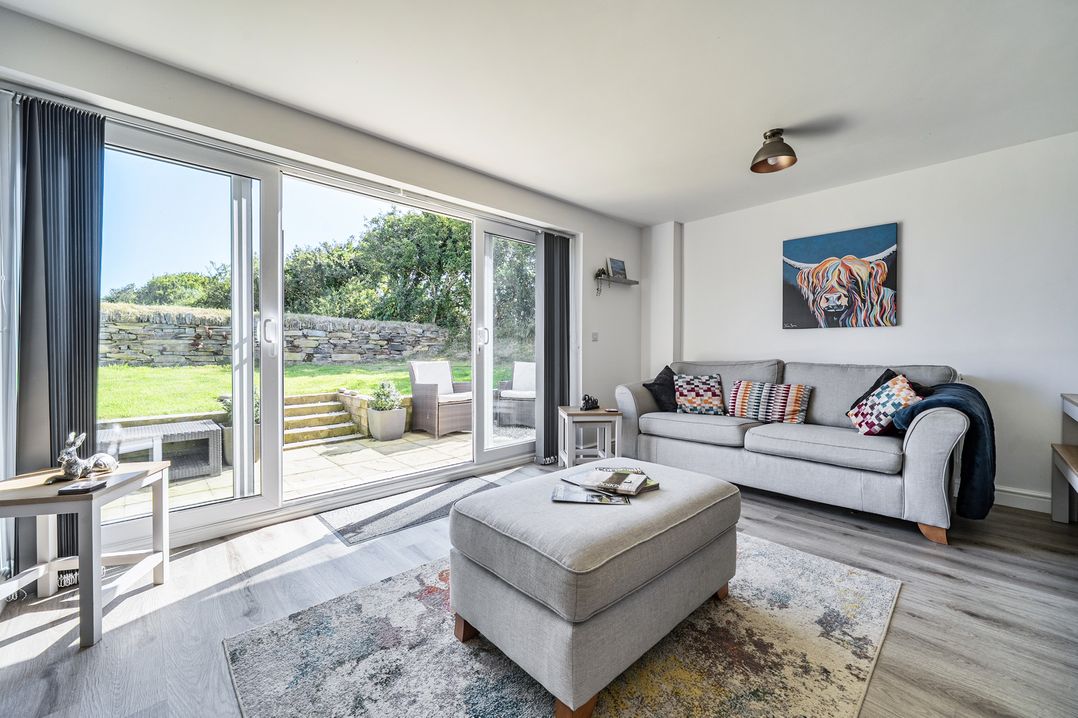 A living room with a sliding door to an outdoor area at Buttercup Cottage St Merryn
