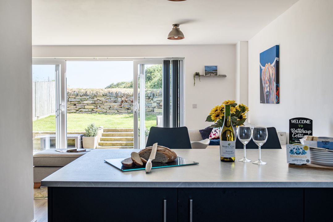A kitchen with an island and seating area at Buttercup Cottage in St Merryn