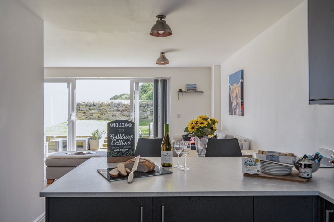 A kitchen with a welcome sign and dining area at Buttercup Cottage St Merryn