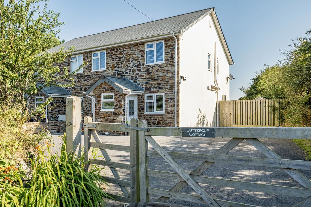 A house with stone exterior and gate at Buttercup Cottage St Merryn