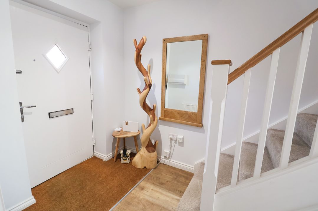A hallway with a door, mirror, and decorative sculpture at Lapwings, Aldeburgh