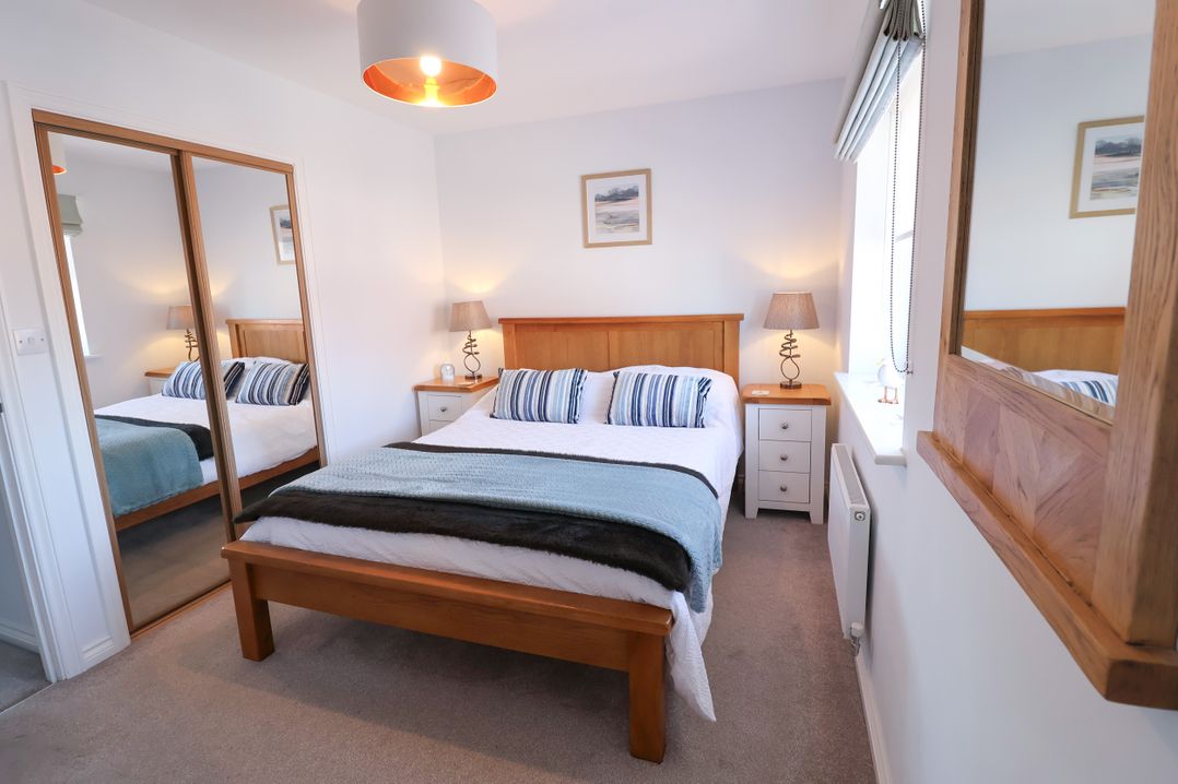 A bedroom with a bed and bedside tables at Lapwings, Aldeburgh