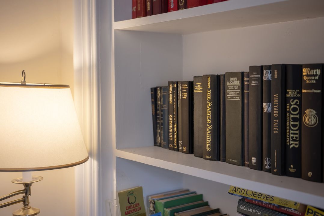 A living room with a lamp and books on a shelf at Edengrove Aberfeldy