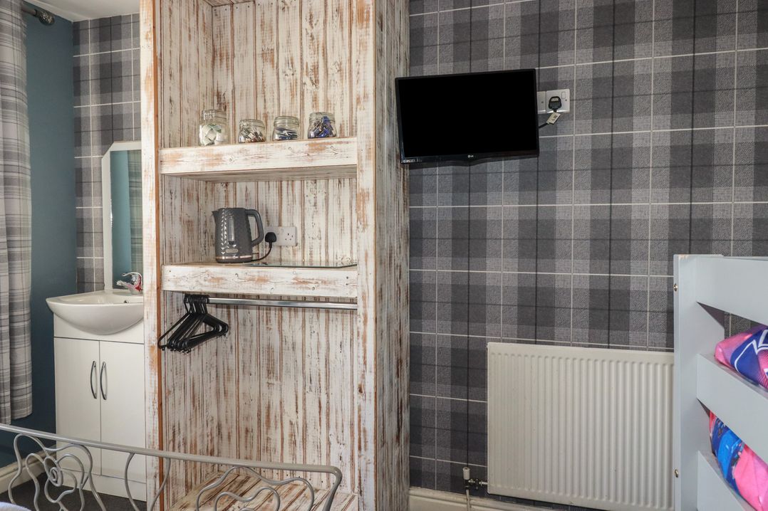A bedroom with a shelf and tv at Shoreline Apartment No.8 in Newquay
