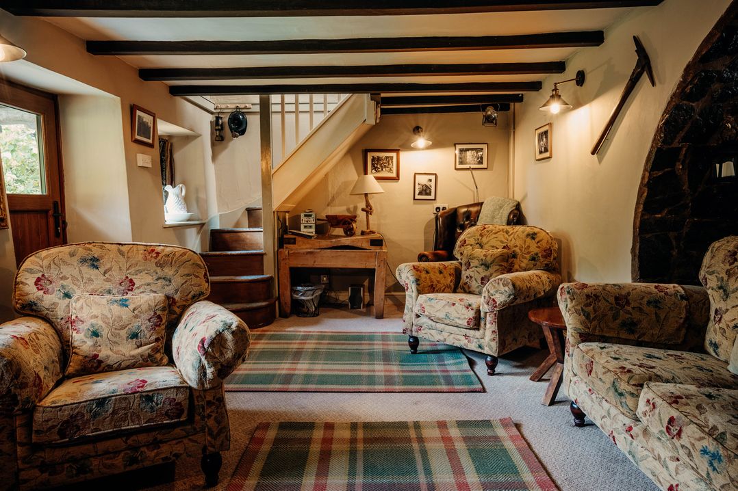 A snug with floral sofas and a staircase at The Wilderness in Stiperstones