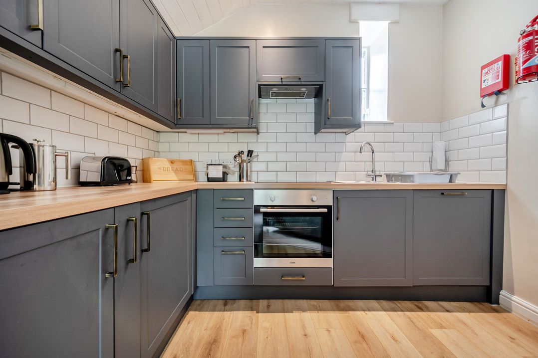 A kitchen with cabinets, an oven, and a sink at Can Brow at the Graythwaite Estate near Hawkshead