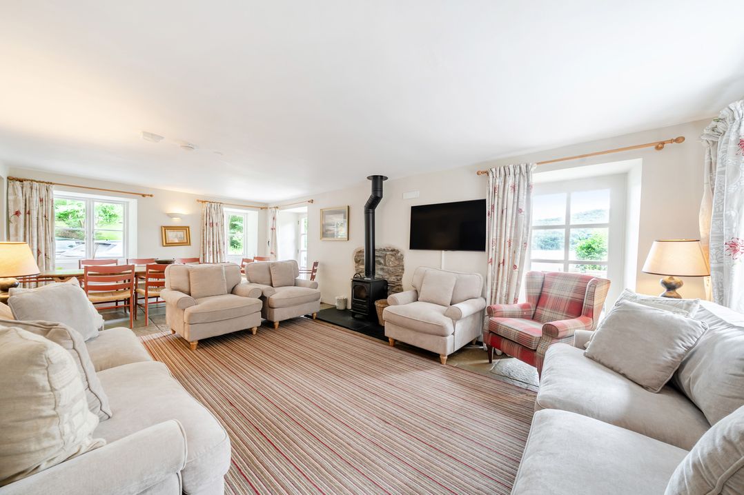 A living room with sofas, armchair, and dining area at Hammerhole at the Graythwaite Estate near Hawkshead