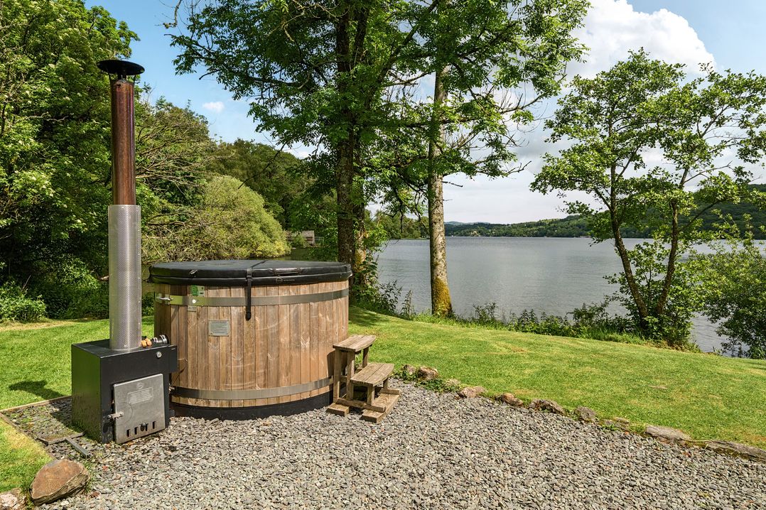 A hot tub with a wooden structure beside a lake at Hullet Hall at the Graythwaite Estate near Hawkshead