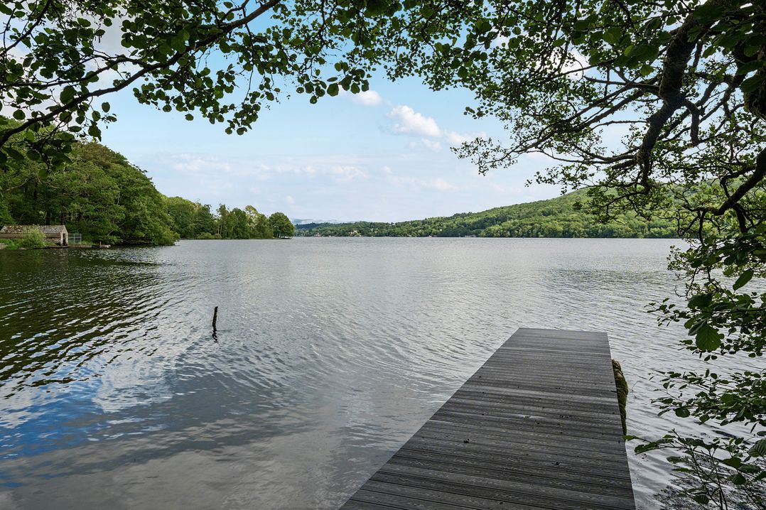 A lake view with a dock and trees at Hullet Hall at the Graythwaite Estate near Hawkshead