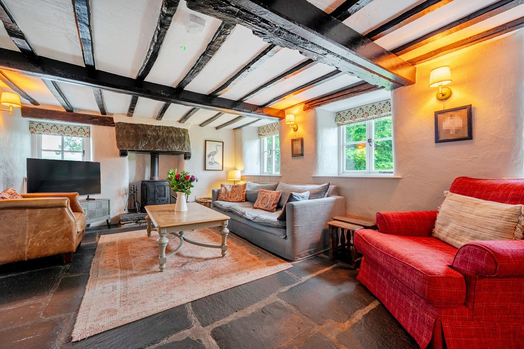 A living room with a sofa, armchair, coffee table and fireplace at Hullet Hall at the Graythwaite Estate near Hawkshead