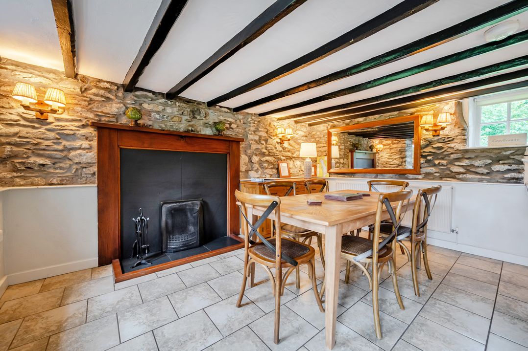 A dining room with a fireplace and wooden table at Hullet Hall at the Graythwaite Estate near Hawkshead