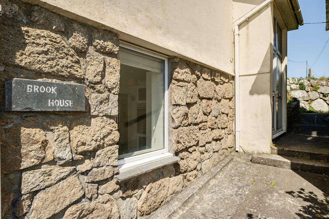 The exterior wall of Brook House with a stone finish and window at Brook House in Sennen Cove near St Just