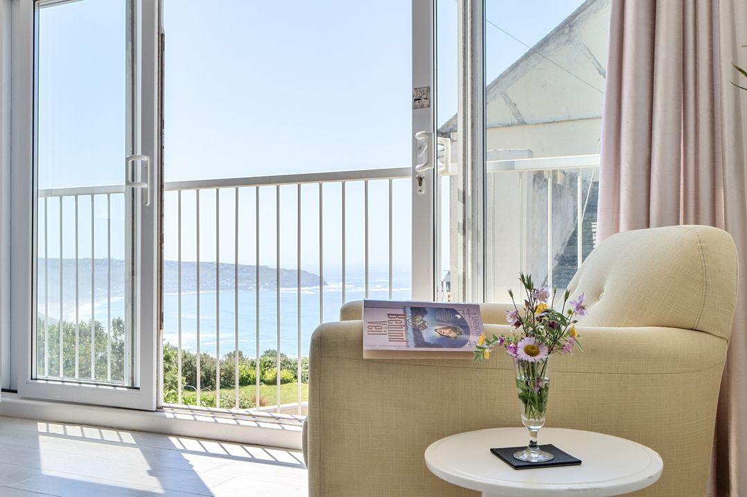 A living room with a sofa and glass table at Brook House Sennen Cove near St Just
