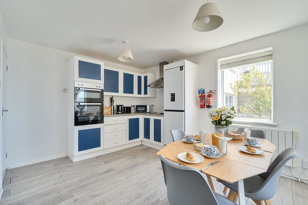 A kitchen with appliances and dining table at Brook House Sennen Cove near St Just