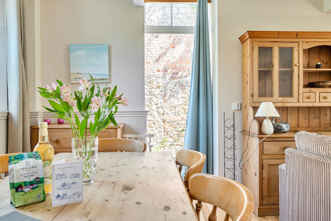 A dining room with a wooden table and flowers at East Wing in Crewkerne