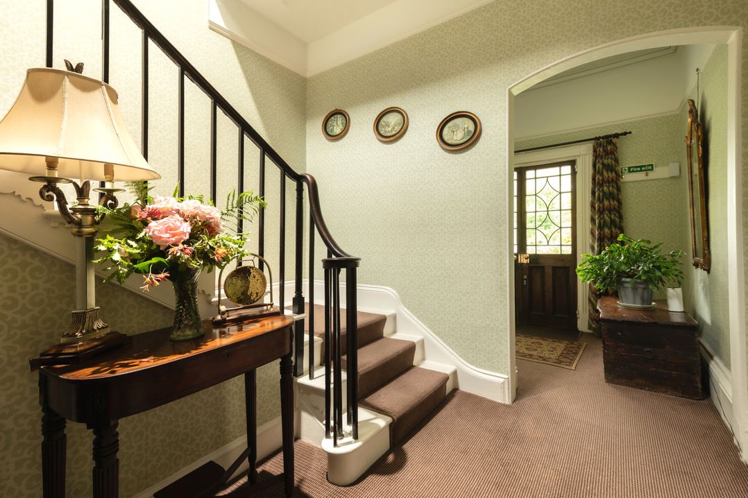 A hallway with a staircase and flower arrangement at Parnacott in Holsworthy