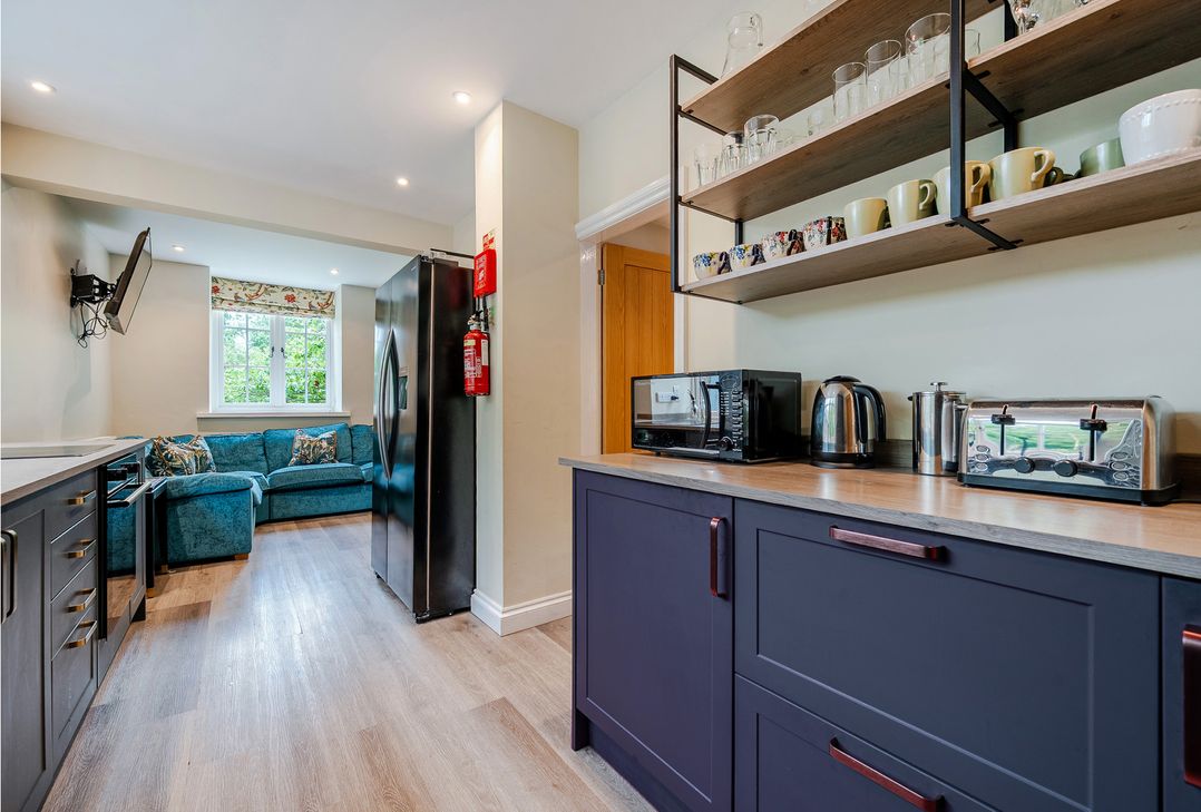 A kitchen with appliances and a sofa at Home Farmhouse at the Graythwaite Estate near Hawkshead