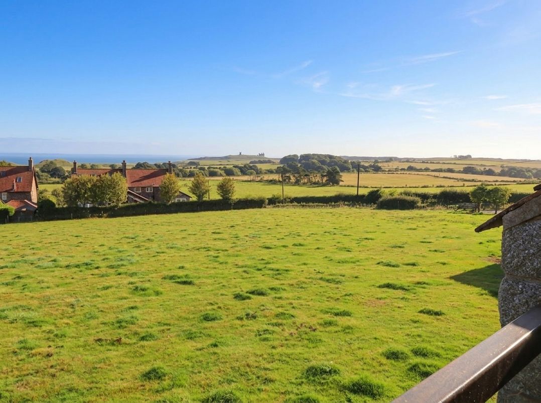 A view of houses and greenery with the ocean in the background at Links View in Embleton
