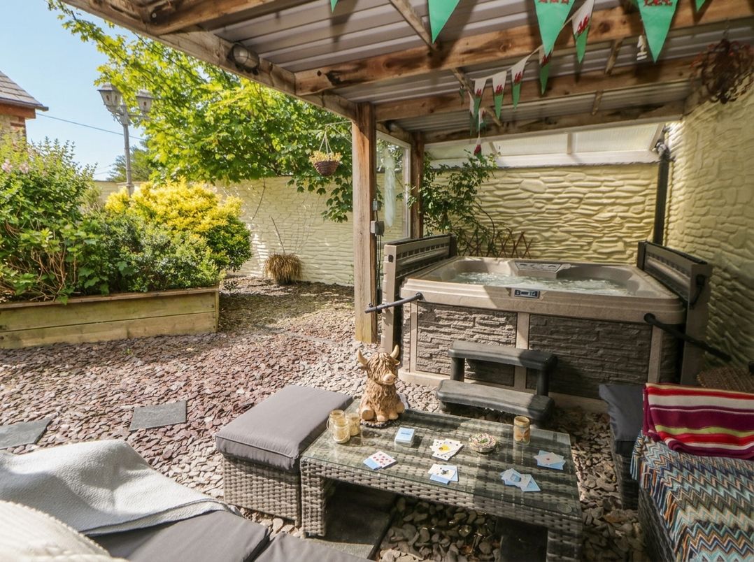 A garden area with a hot tub and outdoor seating at Yr Hen Llaethdy in Blaen-Cil-Llech near Newcastle Emlyn