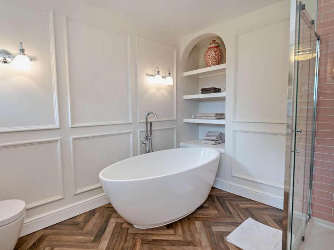 A bathroom with a bathtub and shelving at Luxurious 5 Bedroom House in Cookham near Marlow