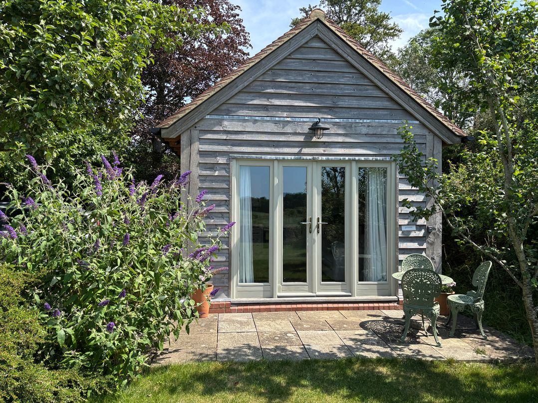 A garden with a building featuring glass doors at The Lodge at Mortons in Hankerton
