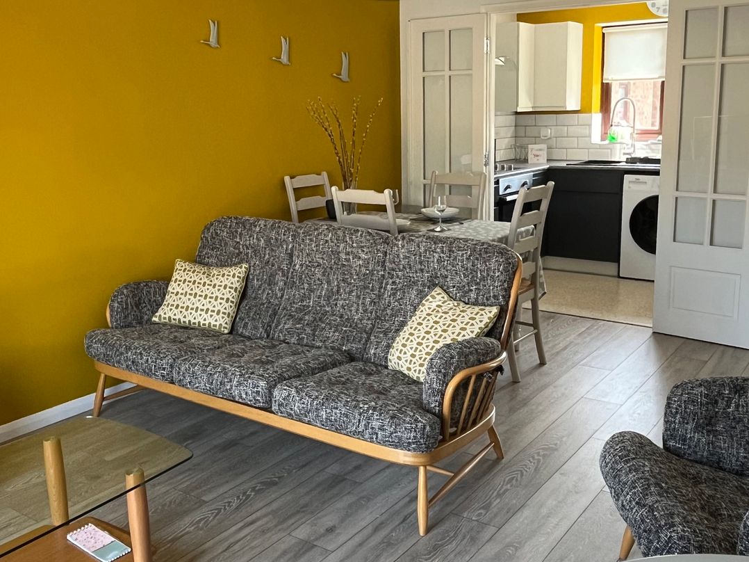 A living room with a sofa and dining area at Village Retreat in Littleport