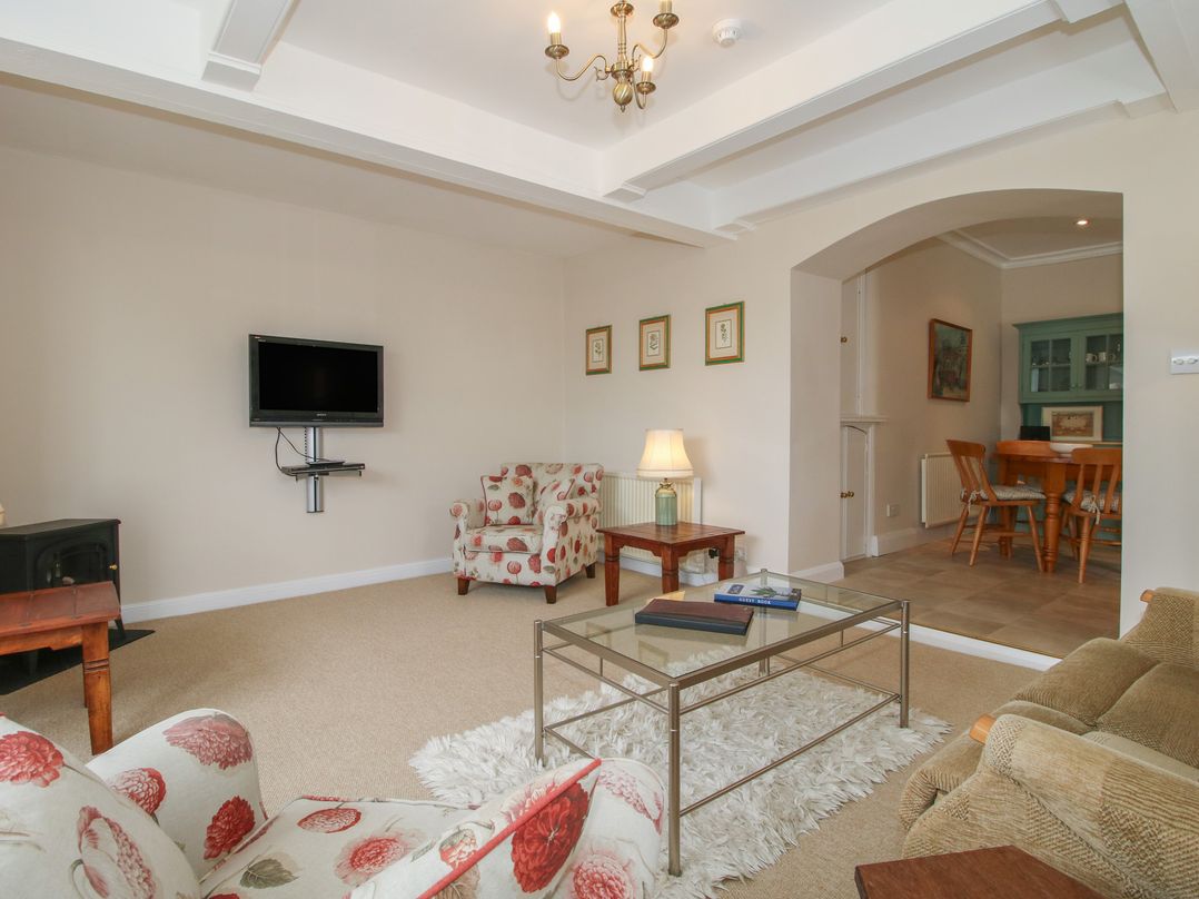 A living room with a sofa, armchair, and television at The Old Nursery in Bourton near Much Wenlock