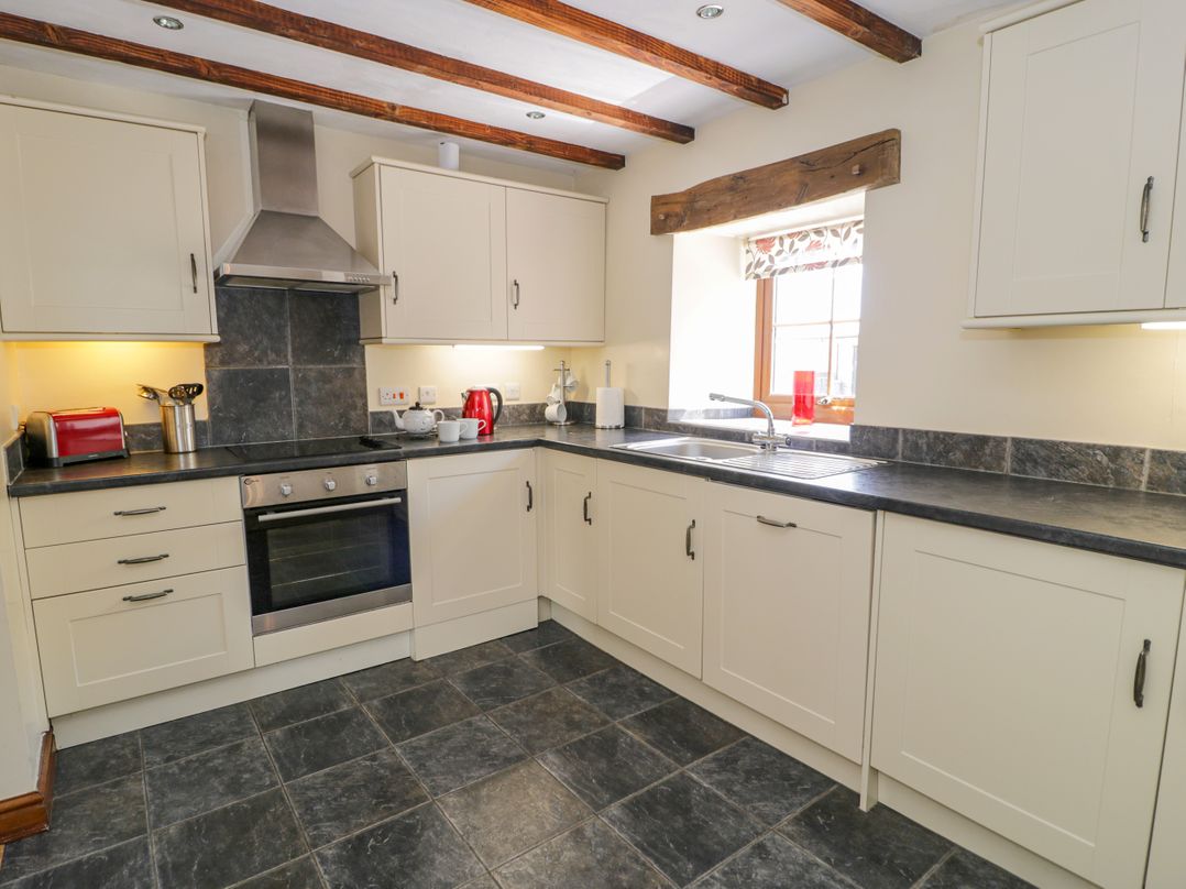 A kitchen with cabinets, stove, sink, and small appliances at Stabal-y-Gwedd, Dolwen near Abergele