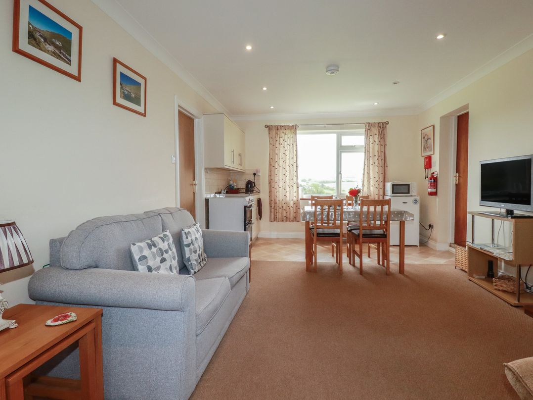 A living room with a sofa and dining area at Little Lanes in Boscastle