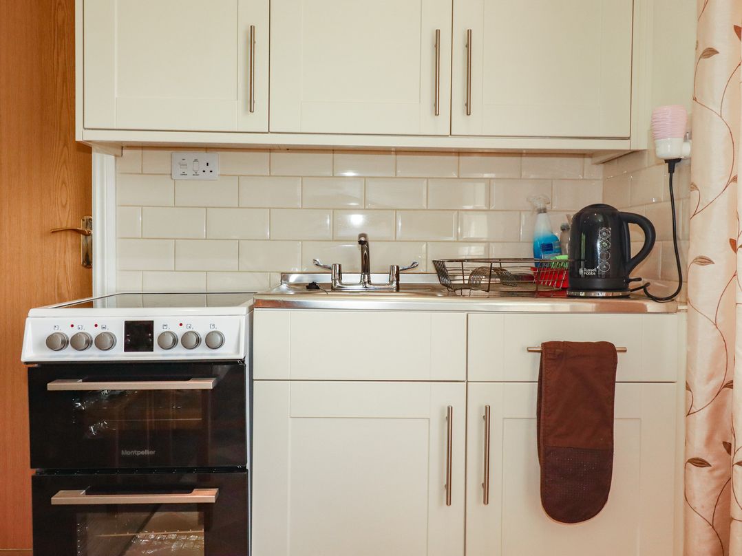 A kitchen with an oven, sink, kettle, and dish rack at Little Lanes in Boscastle
