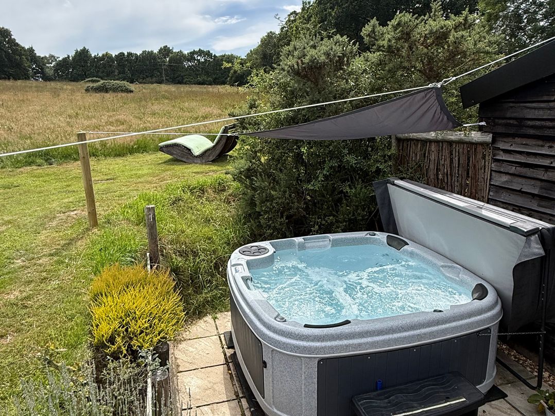 An outdoor area with a hot tub and a hammock at Deer Lodge in Wimborne Minster