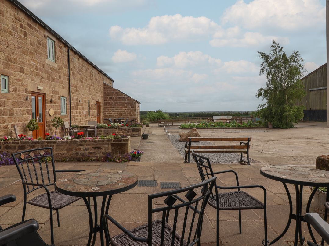 An outdoor area with stone walls, tables, benches and plants at Shepherd's Crook in Follifoot near Spofforth