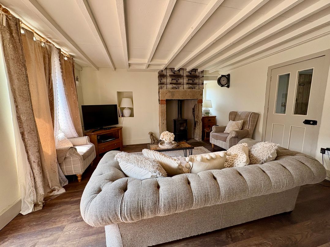 A living room with a sofa, armchair, and fireplace at Coupling Cottage in Belper