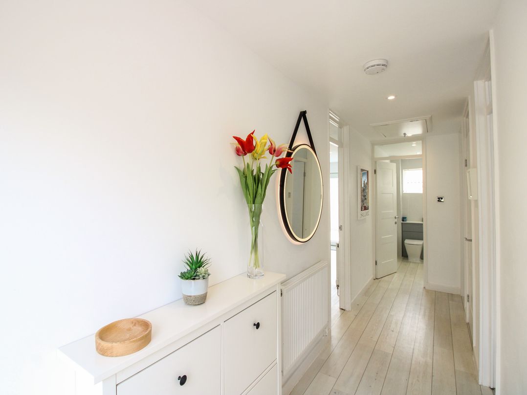A hallway with a mirror and flowers at Little Starboard in Kingsbridge