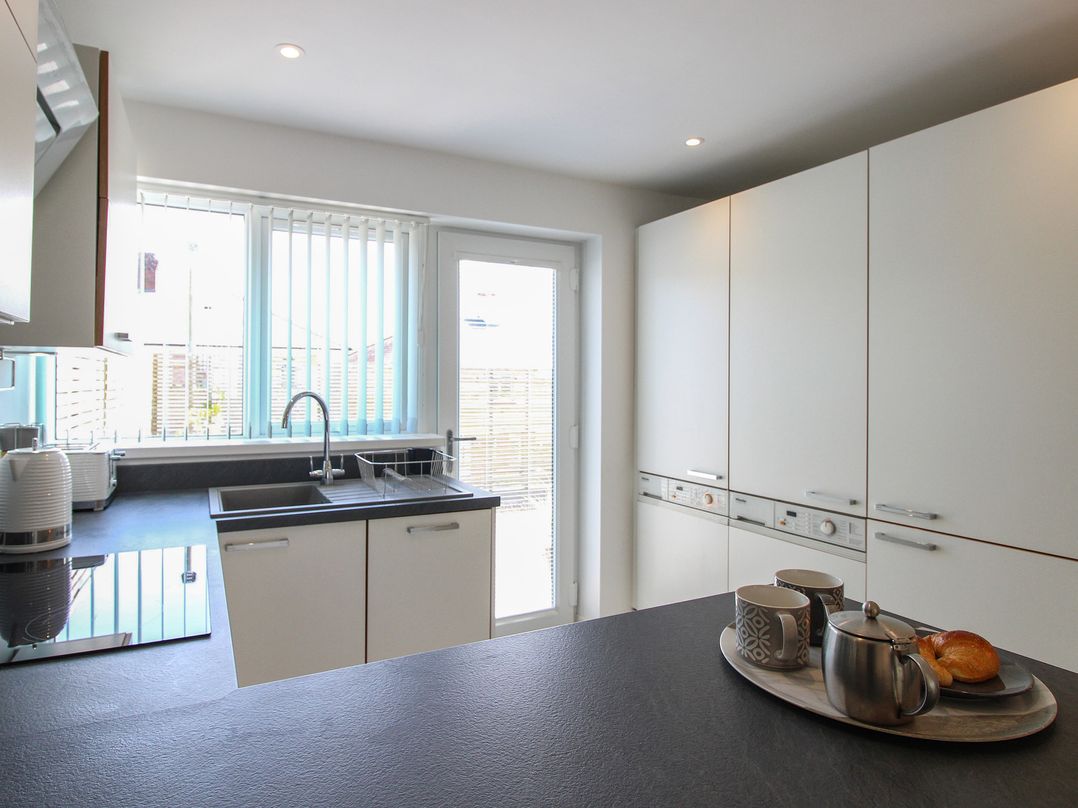A kitchen with a sink and cups on the counter at Little Starboard in Kingsbridge