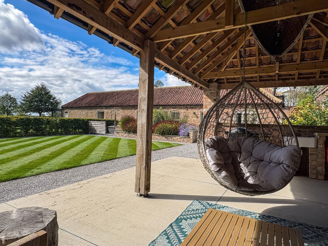 An outdoor area with a hanging chair and table at Flittermouse Barn in Hornsea