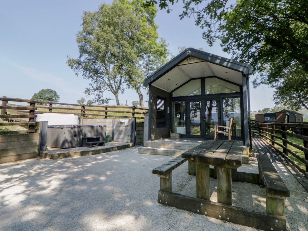 An outdoor area with a hot tub and picnic table at Woodland Escape in Rhayader