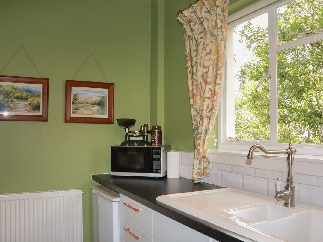 A kitchen area with a sink and microwave at Branklyn Garden Cottage in Perth