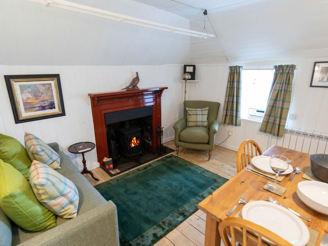 A living room with a fireplace and dining area at Beaton's Croft House - Uig Skye