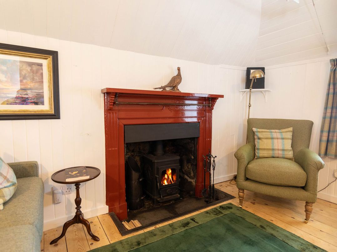 A living room with a fireplace and furniture at Beaton's Croft House - Uig Skye