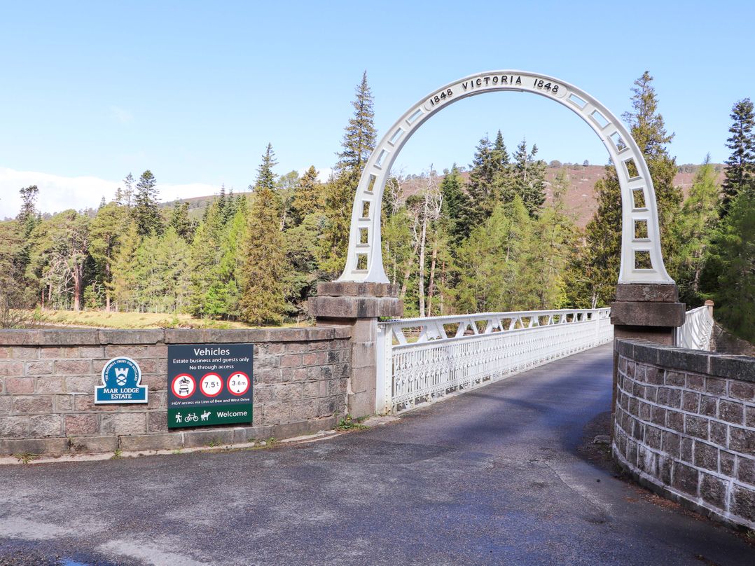 A bridge with a sign and trees at Mar Lodge Estate in Braemar