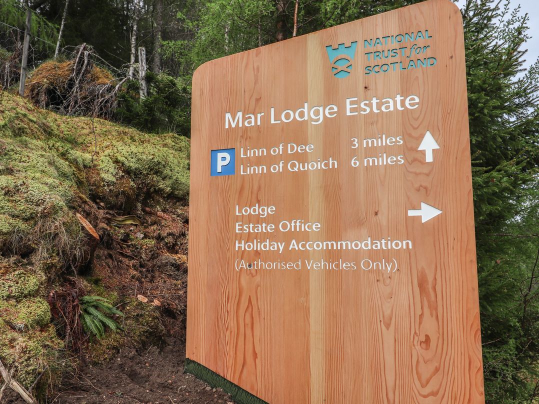 A directional sign for Mar Lodge Estate in the woods at Dalvorar - Mar Lodge Estate Braemar