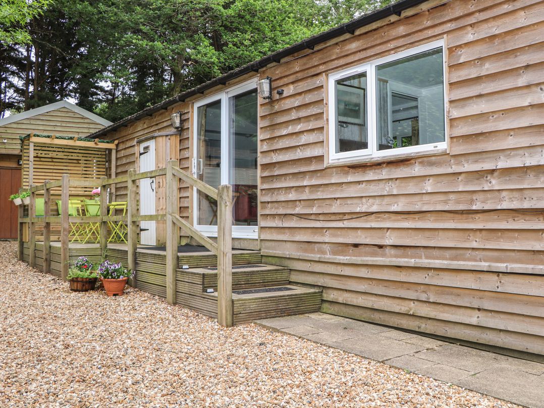 An outdoor area with steps leading to a wooden building at Orchard Lodge in Bolney