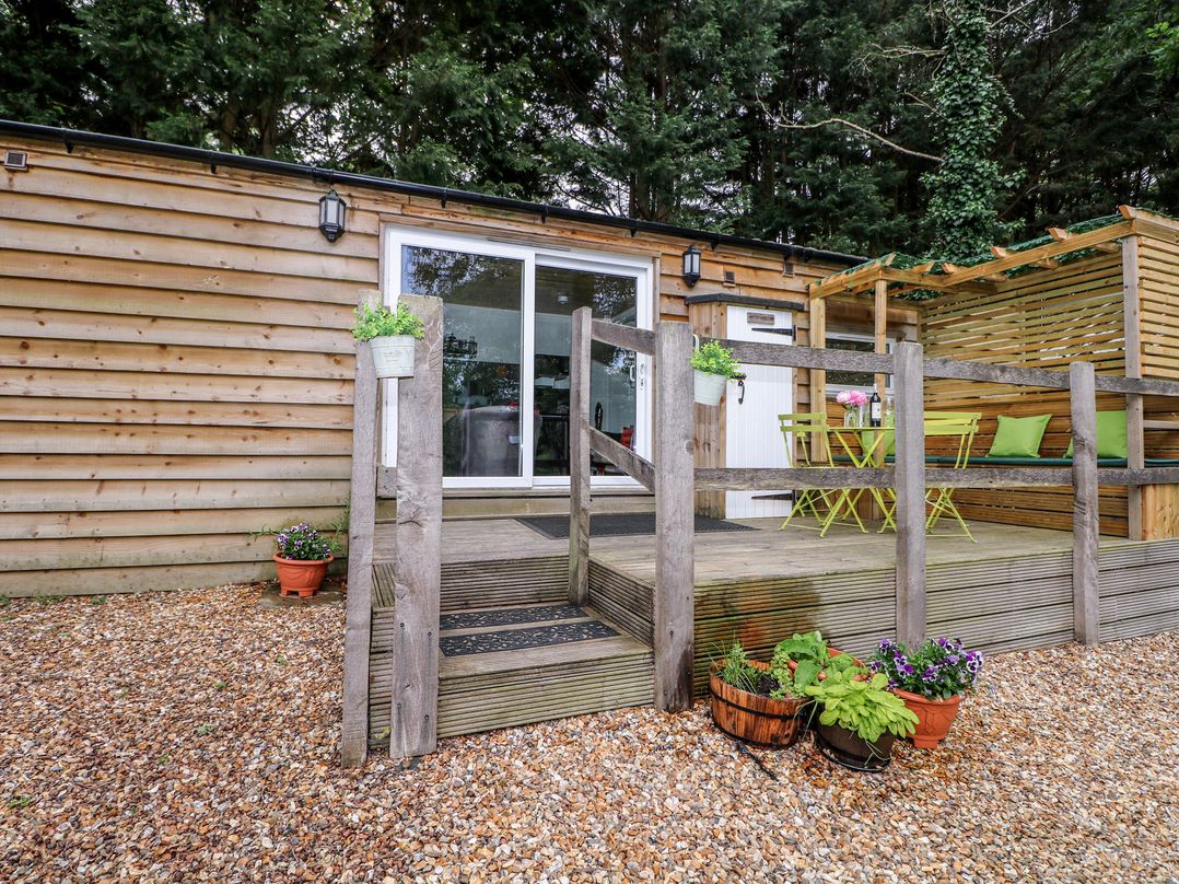 An outdoor area with steps leading to a glass door and seating at Harvest Lodge in Wineham near Bolney