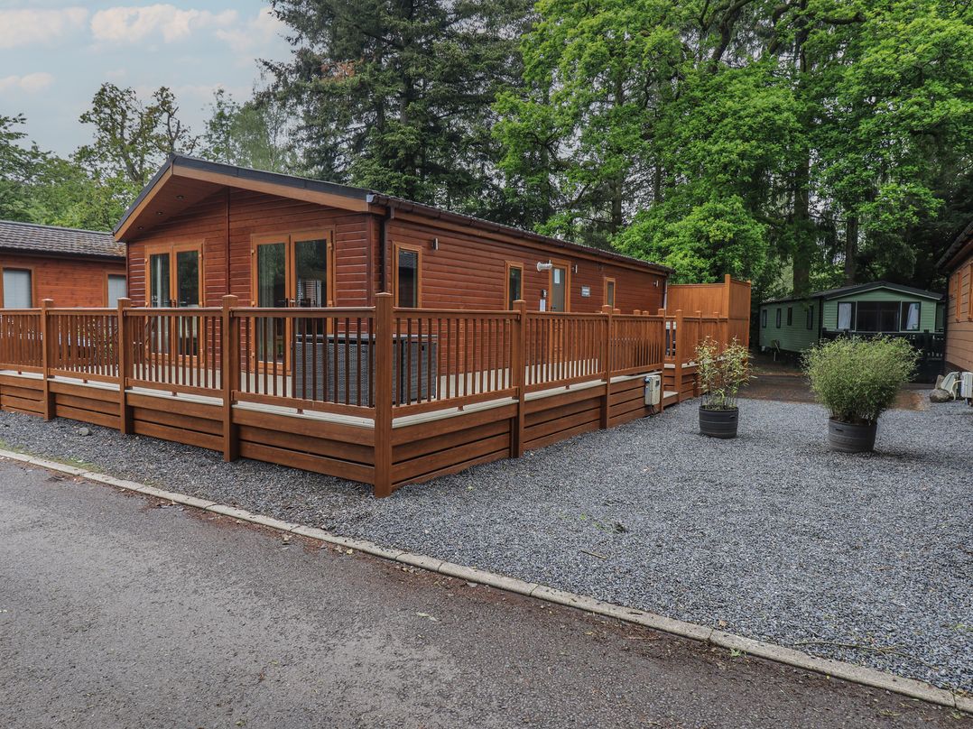 A wooden lodge with decking and gravel area at Ridgway Lodge Calgarth 40 White Cross Bay near Windermere